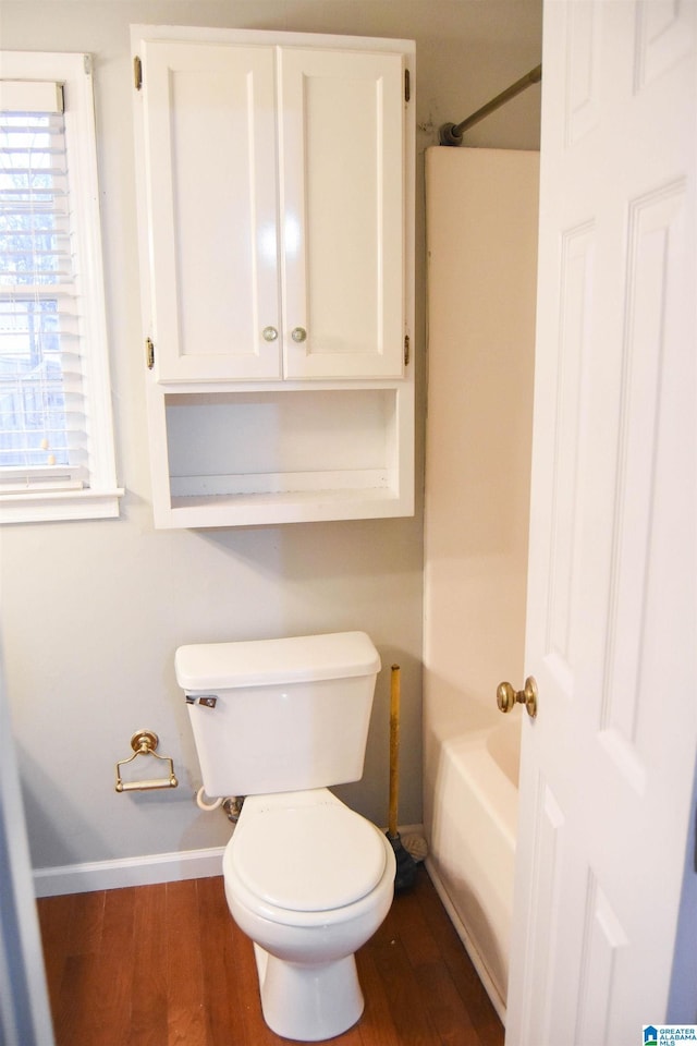 bathroom with toilet, a healthy amount of sunlight, and wood-type flooring