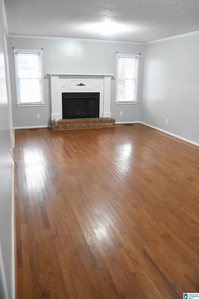 unfurnished living room featuring a brick fireplace, a wealth of natural light, dark hardwood / wood-style flooring, and crown molding