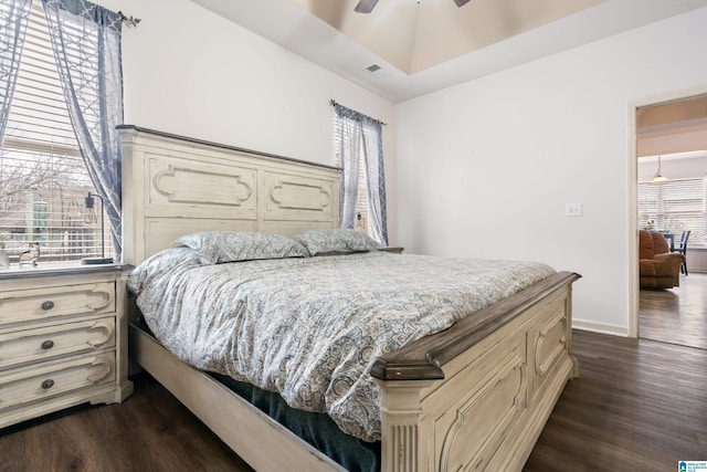 bedroom with multiple windows, ceiling fan, and dark hardwood / wood-style flooring