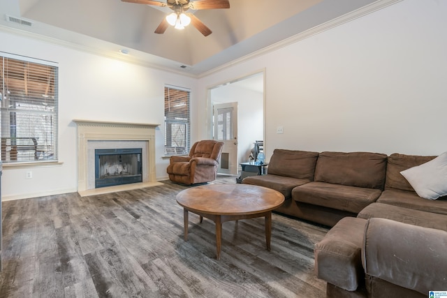 living room featuring wood-type flooring, crown molding, ceiling fan, and a raised ceiling