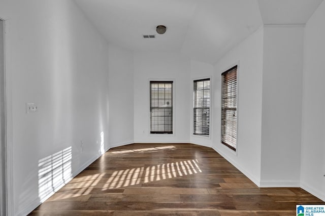 spare room featuring dark hardwood / wood-style flooring and lofted ceiling