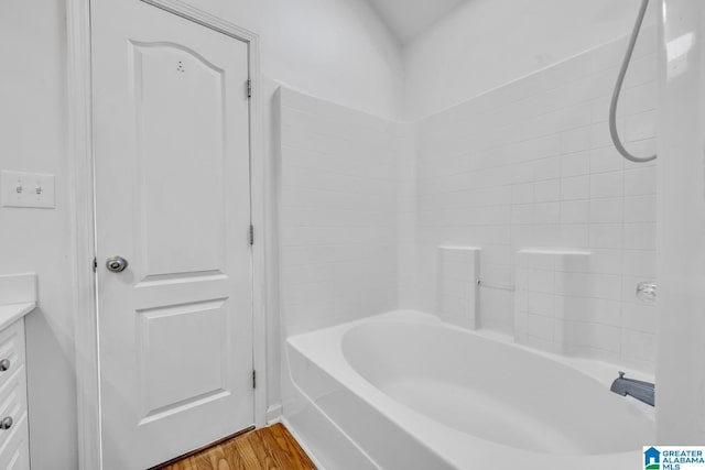 bathroom with washtub / shower combination, wood-type flooring, and vanity