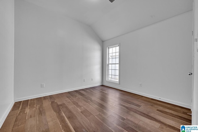 spare room with lofted ceiling and hardwood / wood-style flooring