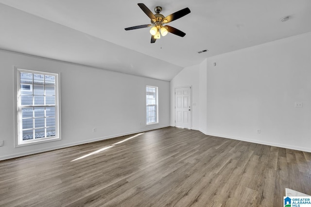 unfurnished room with ceiling fan, a healthy amount of sunlight, vaulted ceiling, and hardwood / wood-style flooring