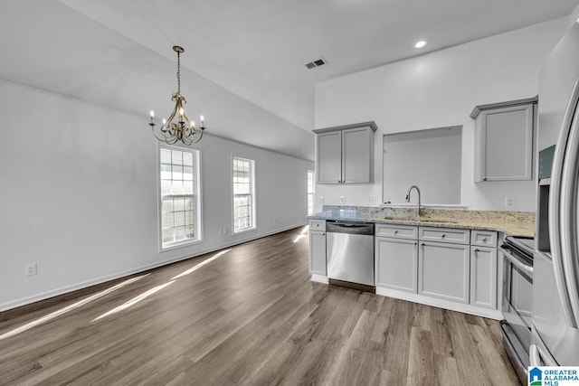 kitchen featuring hardwood / wood-style floors, stainless steel appliances, gray cabinetry, light stone countertops, and sink