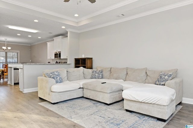 living room featuring ceiling fan with notable chandelier, crown molding, and light hardwood / wood-style flooring