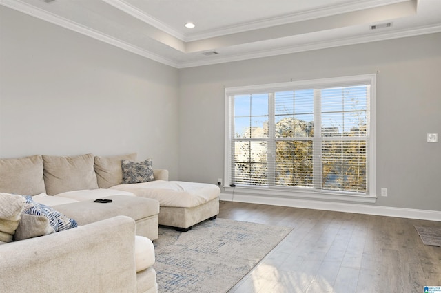 living room featuring hardwood / wood-style flooring, a tray ceiling, and ornamental molding