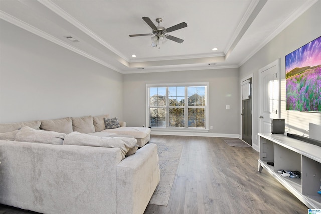 living room with ceiling fan, hardwood / wood-style floors, a tray ceiling, and crown molding