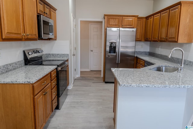 kitchen featuring appliances with stainless steel finishes, tasteful backsplash, sink, light stone counters, and light hardwood / wood-style floors