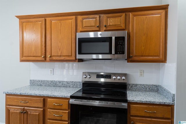 kitchen with decorative backsplash, light stone countertops, and appliances with stainless steel finishes