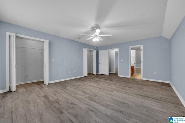 unfurnished bedroom featuring light wood-type flooring, vaulted ceiling, ceiling fan, and ensuite bathroom