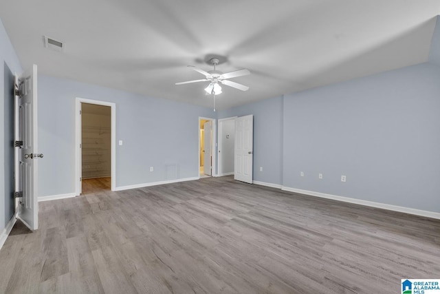 unfurnished bedroom with light hardwood / wood-style flooring, ceiling fan, connected bathroom, a spacious closet, and a closet