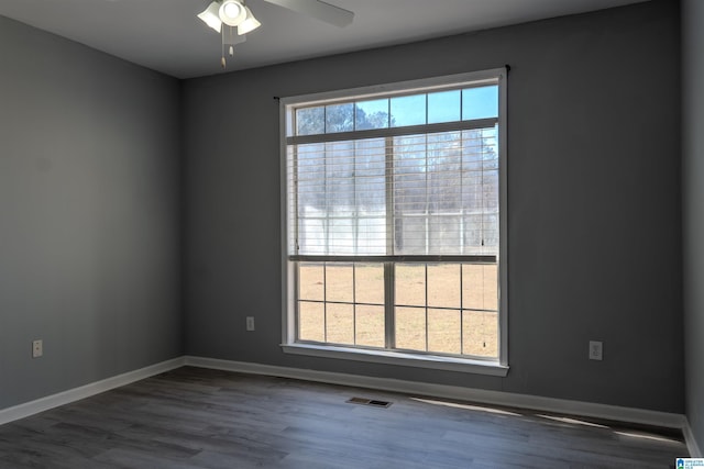 spare room featuring ceiling fan, dark wood-type flooring, and a healthy amount of sunlight