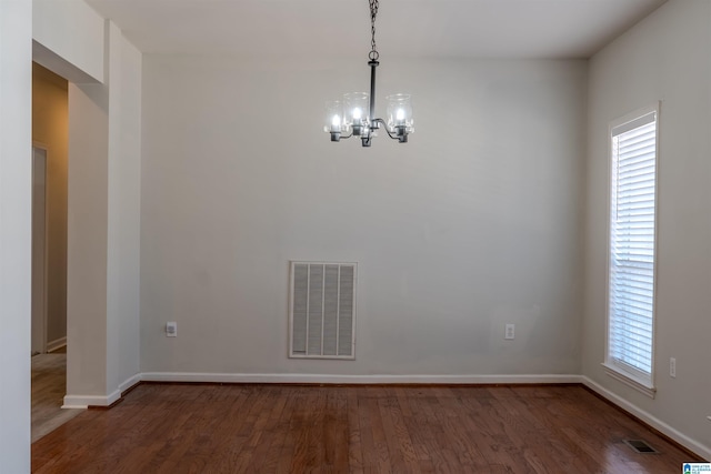 unfurnished dining area featuring an inviting chandelier and dark wood-type flooring