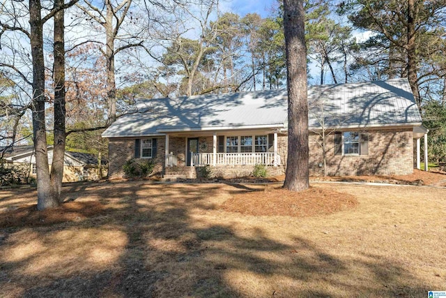 ranch-style home featuring an outdoor structure, covered porch, and a front lawn