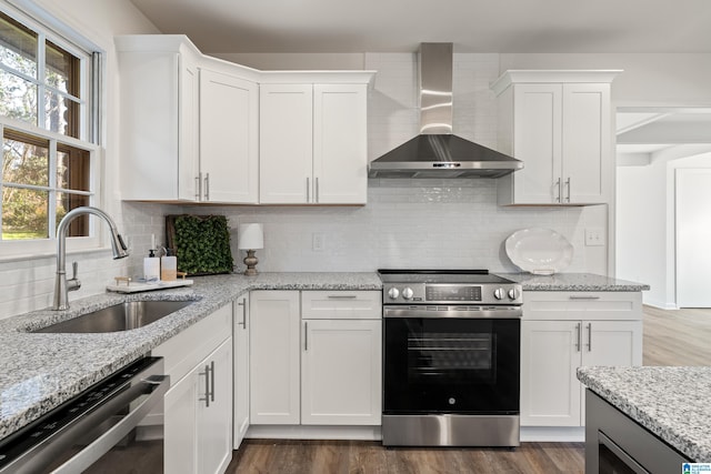 kitchen featuring appliances with stainless steel finishes, wall chimney exhaust hood, white cabinetry, and sink