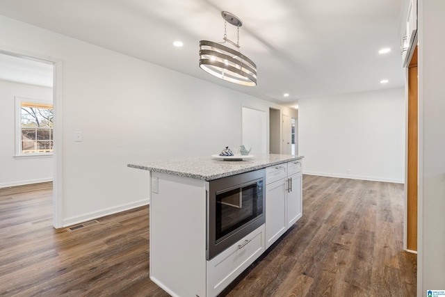 kitchen with white cabinetry, dark hardwood / wood-style floors, decorative light fixtures, built in microwave, and a kitchen island