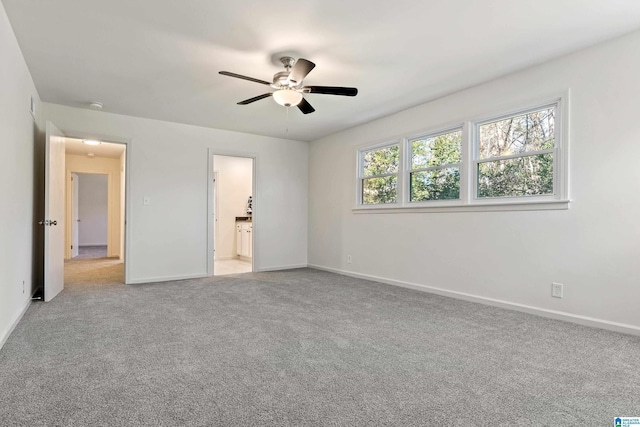 unfurnished bedroom featuring ceiling fan, ensuite bathroom, and light carpet