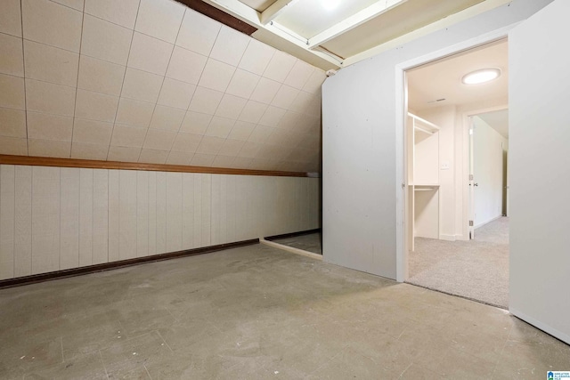 bonus room with light colored carpet and wooden walls