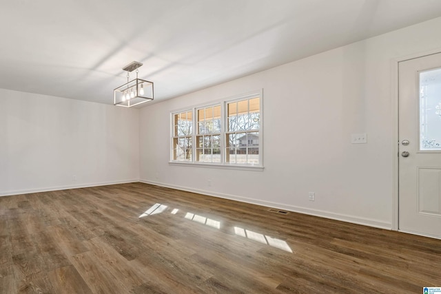 unfurnished dining area with dark hardwood / wood-style floors and a notable chandelier