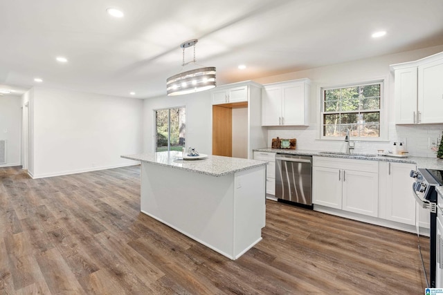 kitchen featuring hanging light fixtures, a kitchen island, stainless steel appliances, and white cabinetry