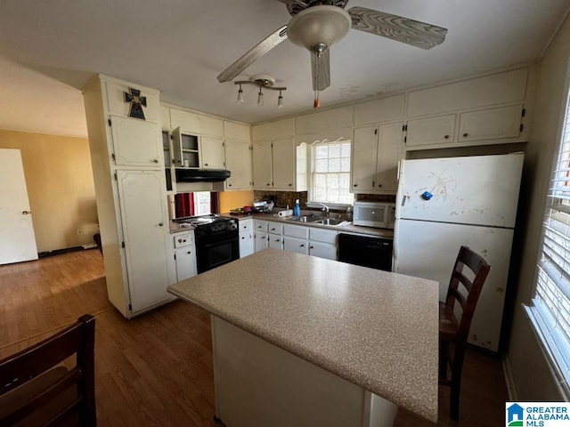 kitchen with ceiling fan, dark hardwood / wood-style floors, black appliances, a breakfast bar, and sink