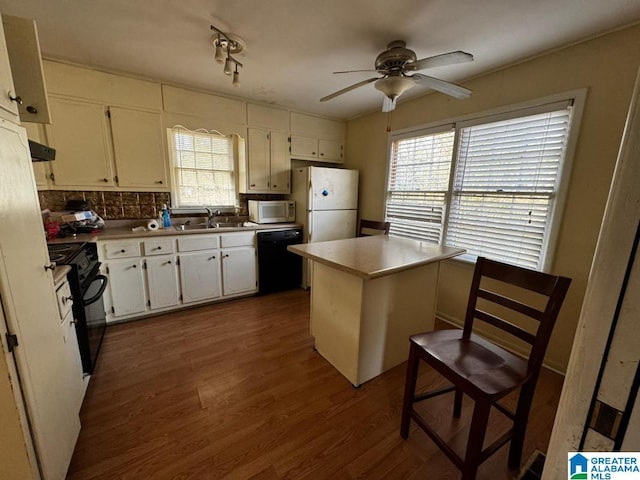 kitchen with a kitchen island, black appliances, sink, white cabinetry, and dark wood-type flooring