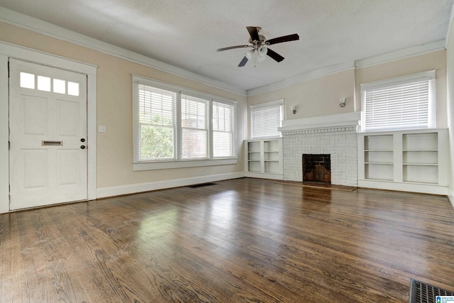 unfurnished living room featuring a textured ceiling, dark hardwood / wood-style flooring, a fireplace, ornamental molding, and ceiling fan