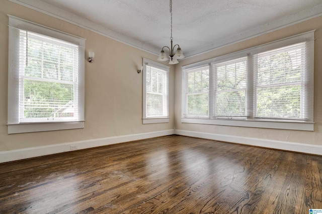 unfurnished dining area with a wealth of natural light, dark hardwood / wood-style flooring, a textured ceiling, and an inviting chandelier