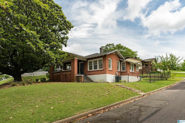 view of front of house with a front lawn and central AC