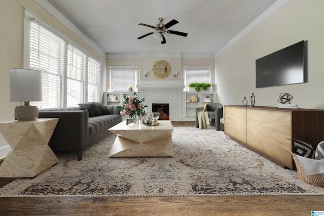 living room with hardwood / wood-style floors, ceiling fan, a textured ceiling, crown molding, and a tile fireplace