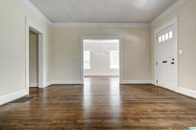 entryway featuring dark wood-type flooring, crown molding, and an inviting chandelier