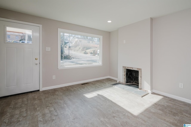 unfurnished living room featuring a tiled fireplace and light hardwood / wood-style flooring