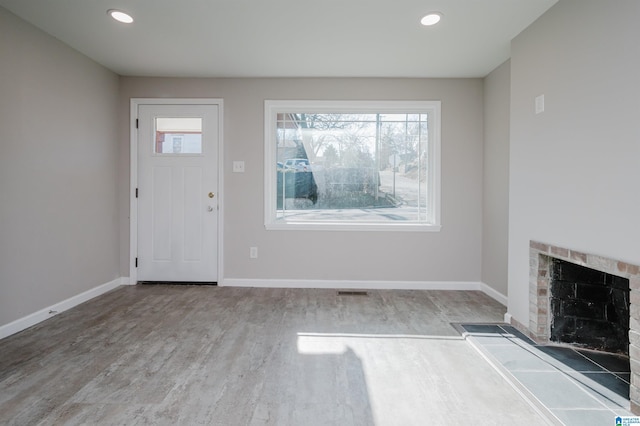 foyer featuring a tiled fireplace and light wood-type flooring