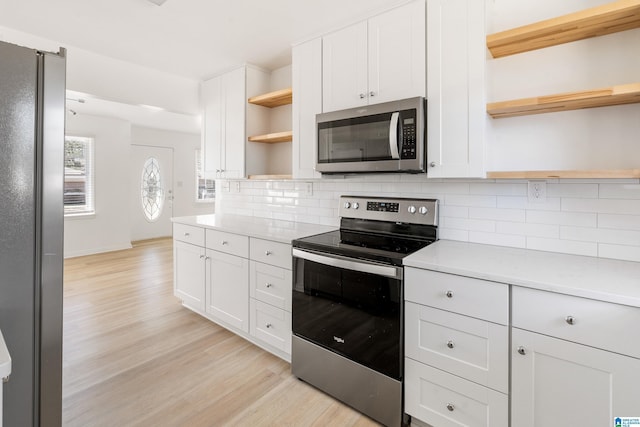 kitchen with white cabinetry, stainless steel appliances, decorative backsplash, light hardwood / wood-style flooring, and light stone counters