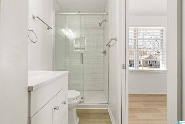 bathroom with a shower with shower door, hardwood / wood-style floors, toilet, and vanity