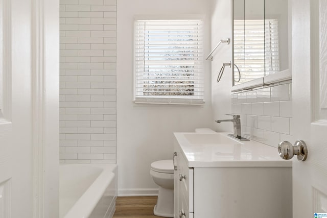 full bathroom with toilet, vanity, tiled shower / bath, and hardwood / wood-style floors