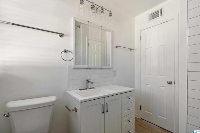 bathroom featuring toilet, vanity, decorative backsplash, and hardwood / wood-style floors