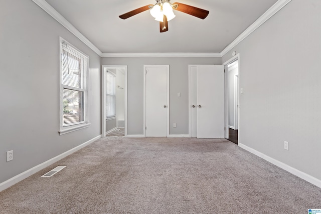 unfurnished bedroom featuring ceiling fan, ensuite bath, ornamental molding, and carpet floors