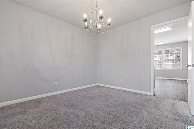 carpeted spare room featuring a notable chandelier