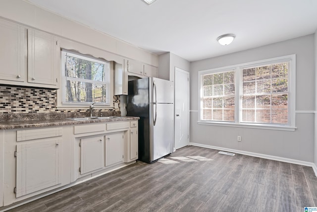 kitchen featuring dark hardwood / wood-style floors, decorative backsplash, stainless steel refrigerator, sink, and white cabinets