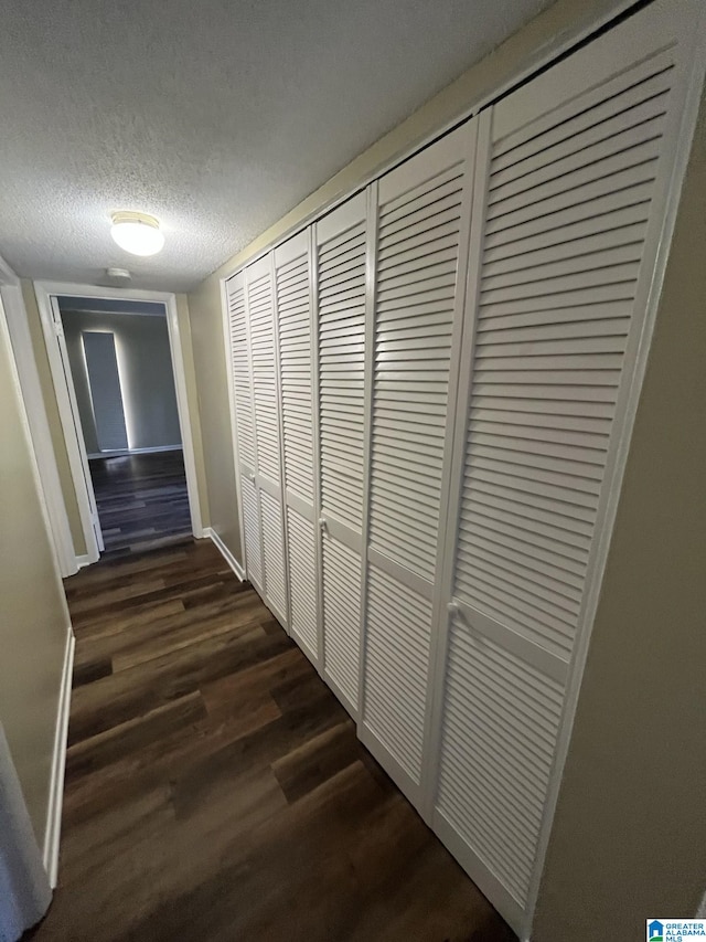 corridor featuring dark hardwood / wood-style floors and a textured ceiling