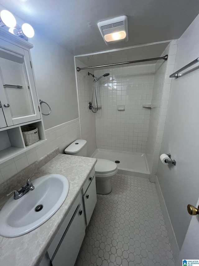 bathroom with backsplash, toilet, tiled shower, and vanity