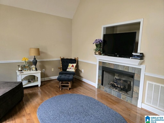 sitting room with lofted ceiling, wood-type flooring, and a tile fireplace