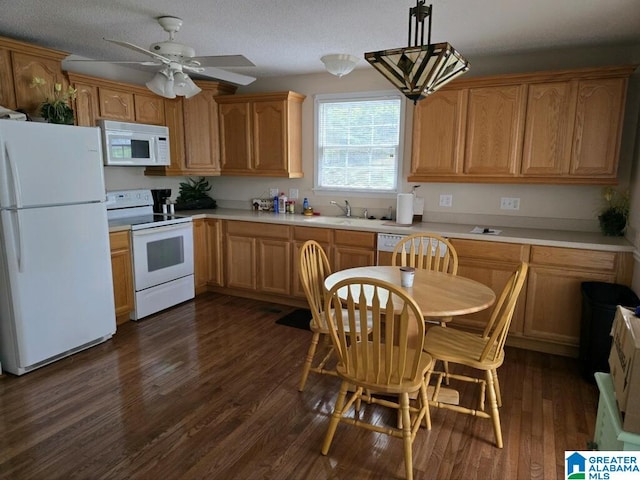 kitchen with white appliances, a textured ceiling, dark wood-type flooring, sink, and hanging light fixtures