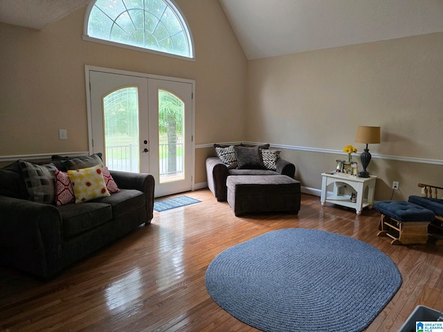 living room with high vaulted ceiling, french doors, and hardwood / wood-style flooring