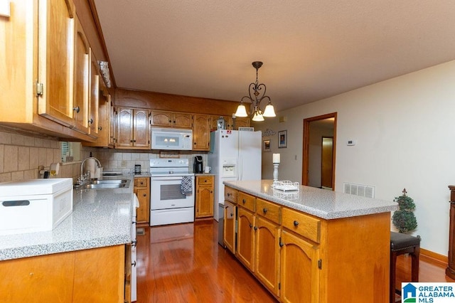 kitchen with pendant lighting, white appliances, a kitchen island, sink, and backsplash