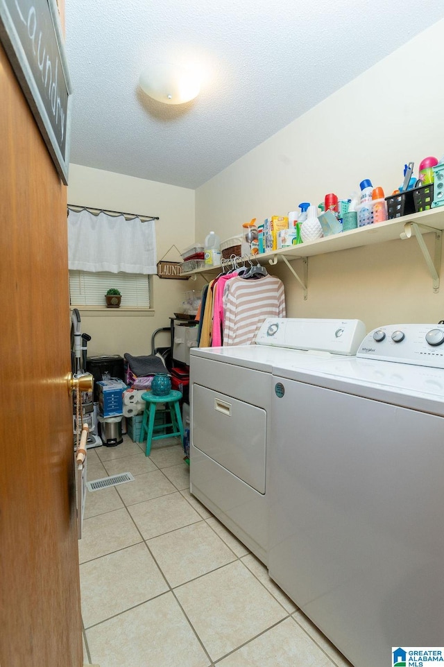 laundry room with light tile patterned floors, washing machine and clothes dryer, and a textured ceiling