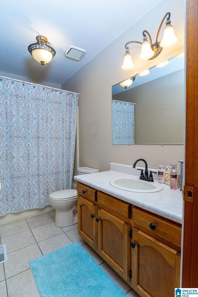 bathroom with toilet, vanity, tile patterned floors, and a textured ceiling