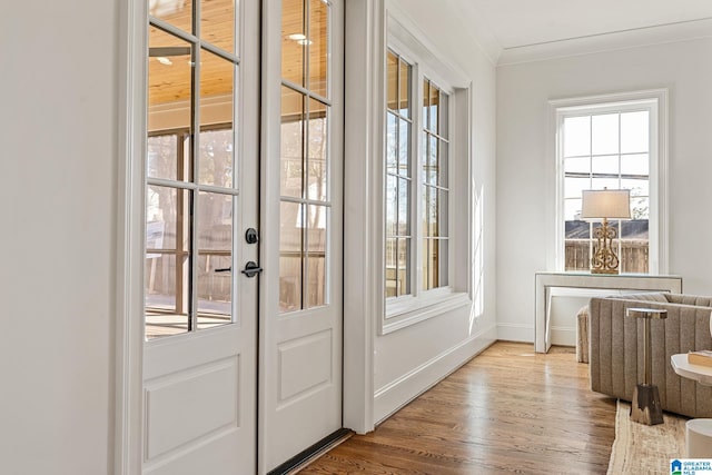 doorway with hardwood / wood-style floors, crown molding, and a healthy amount of sunlight